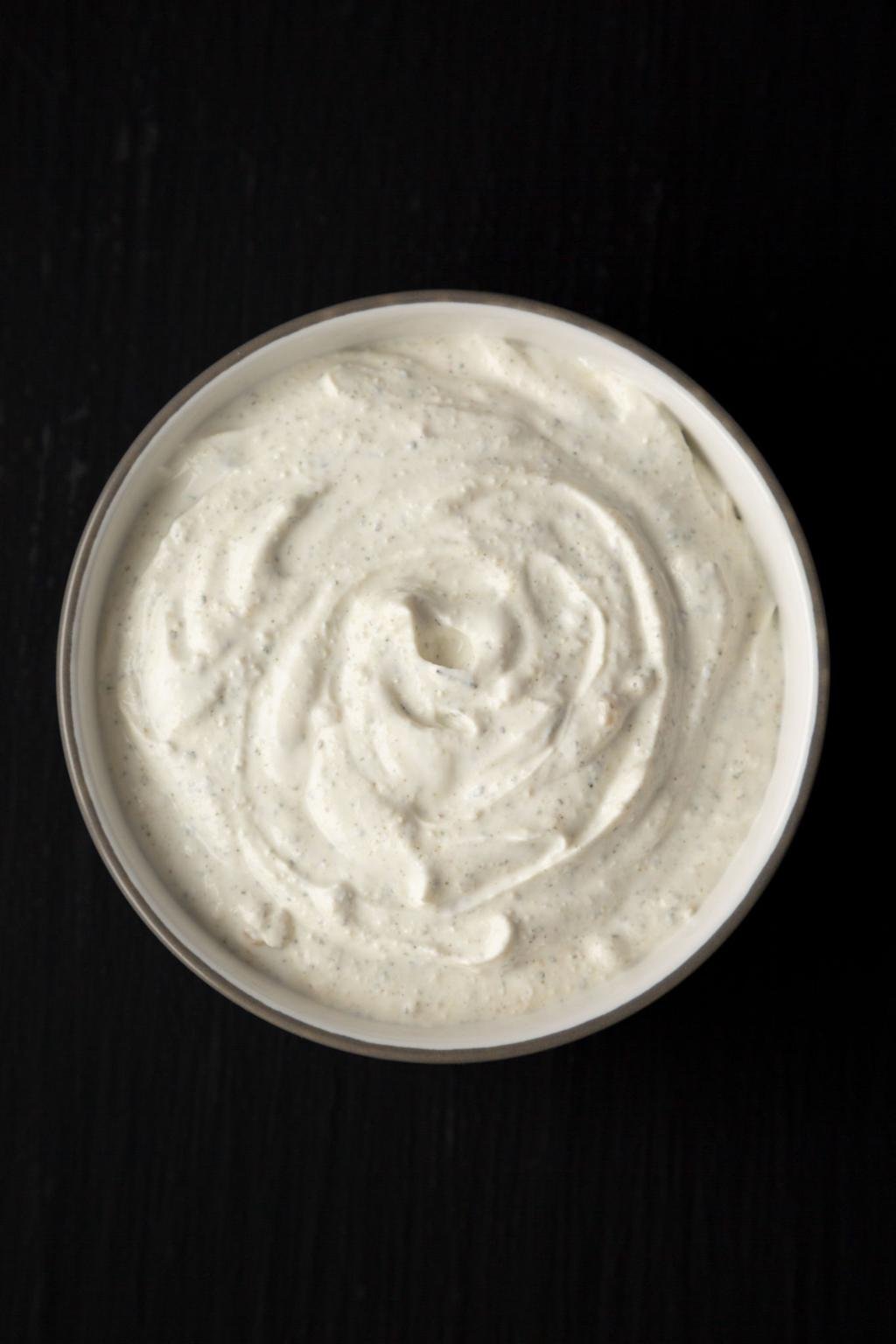Top view of a round container filled with fluffy whipped cream on a dark surface.