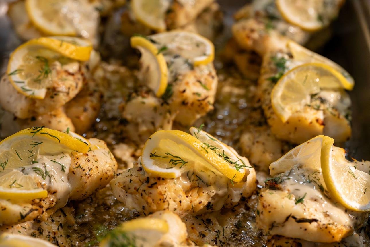 Shrimp bites baked with herbs, lemon slices, and a creamy glaze on a baking sheet