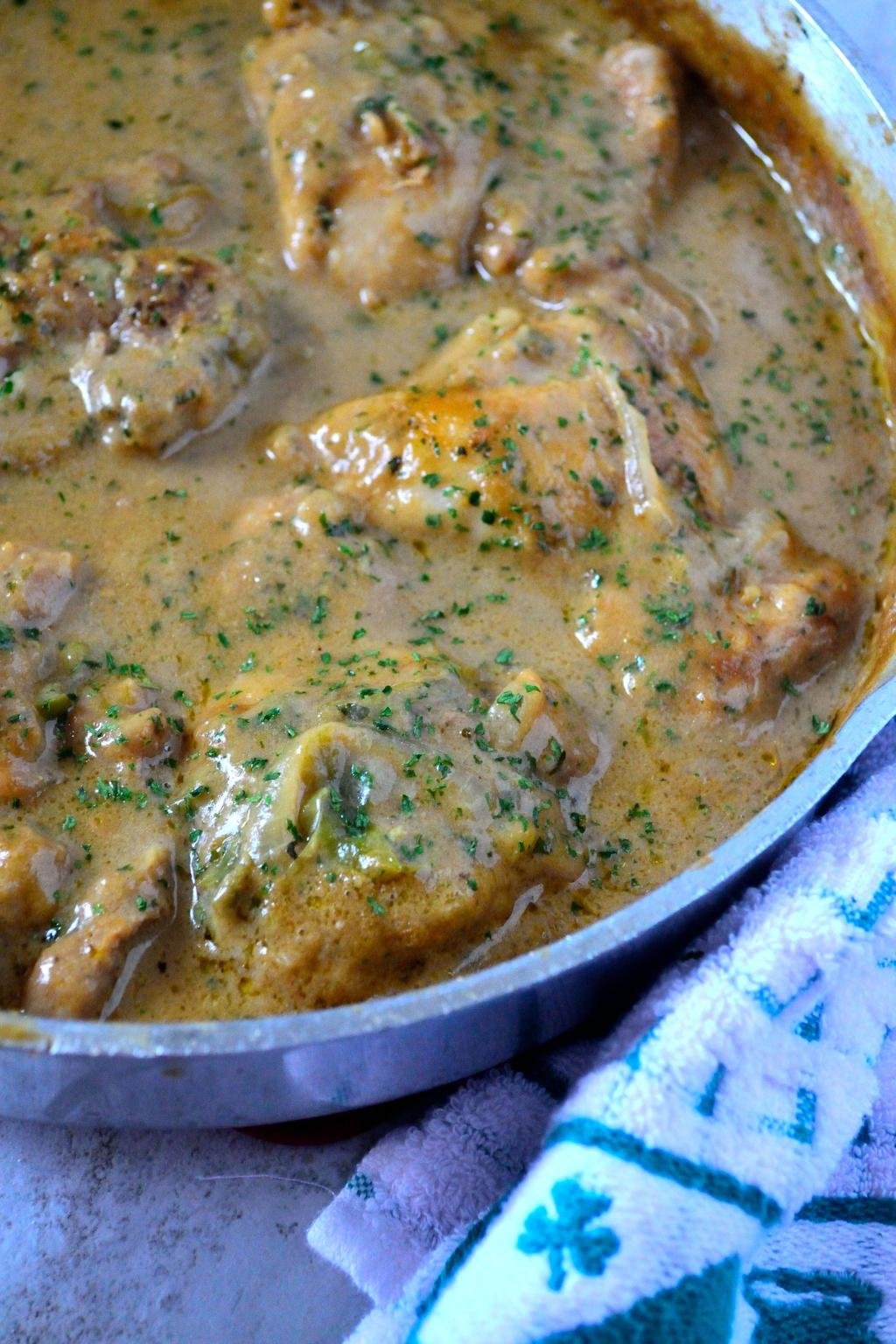 Skillet of creamy chicken in herb sauce with chopped parsley on top