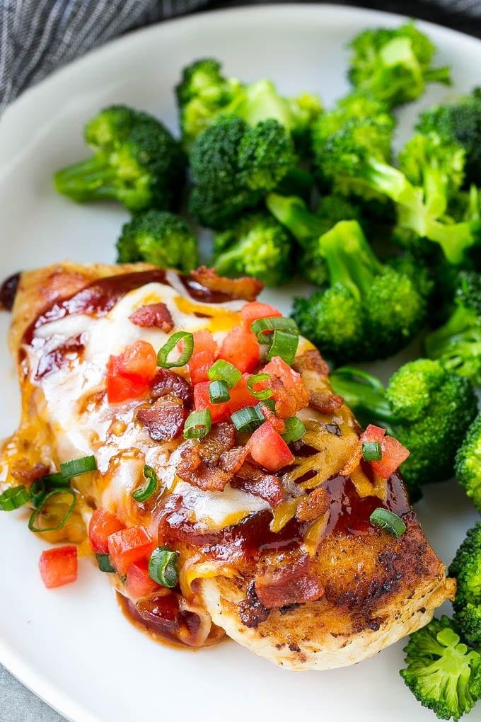 Baked chicken breast topped with melted cheese, bacon, diced tomatoes, and green onions, served with broccoli on the side.